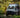 Custom Sprinter camper van with roof lights parked in a forest setting, adventure ready