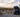 Custom Sprinter van parked at scenic desert campsite with chairs, person, and mountain views
