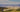 Custom Sprinter vans driving on a dusty mountain trail in the desert landscape