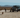 Custom Sprinter van parked in desert with people, dog, and outdoor adventure gear