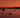 Rocky shoreline at sunset with calm water and coastal hills in the background