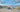 Custom camper van parked in a scenic desert canyon with rocky hills and blue sky