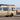 Custom Sprinter adventure van with roof rack and ladder parked by the beach