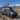 Custom Sprinter van with rooftop solar panels parked in desert mountains, ready for off-grid adventure.
