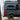 Custom Sprinter van with off-road tires and roof rack parked outdoors near trees