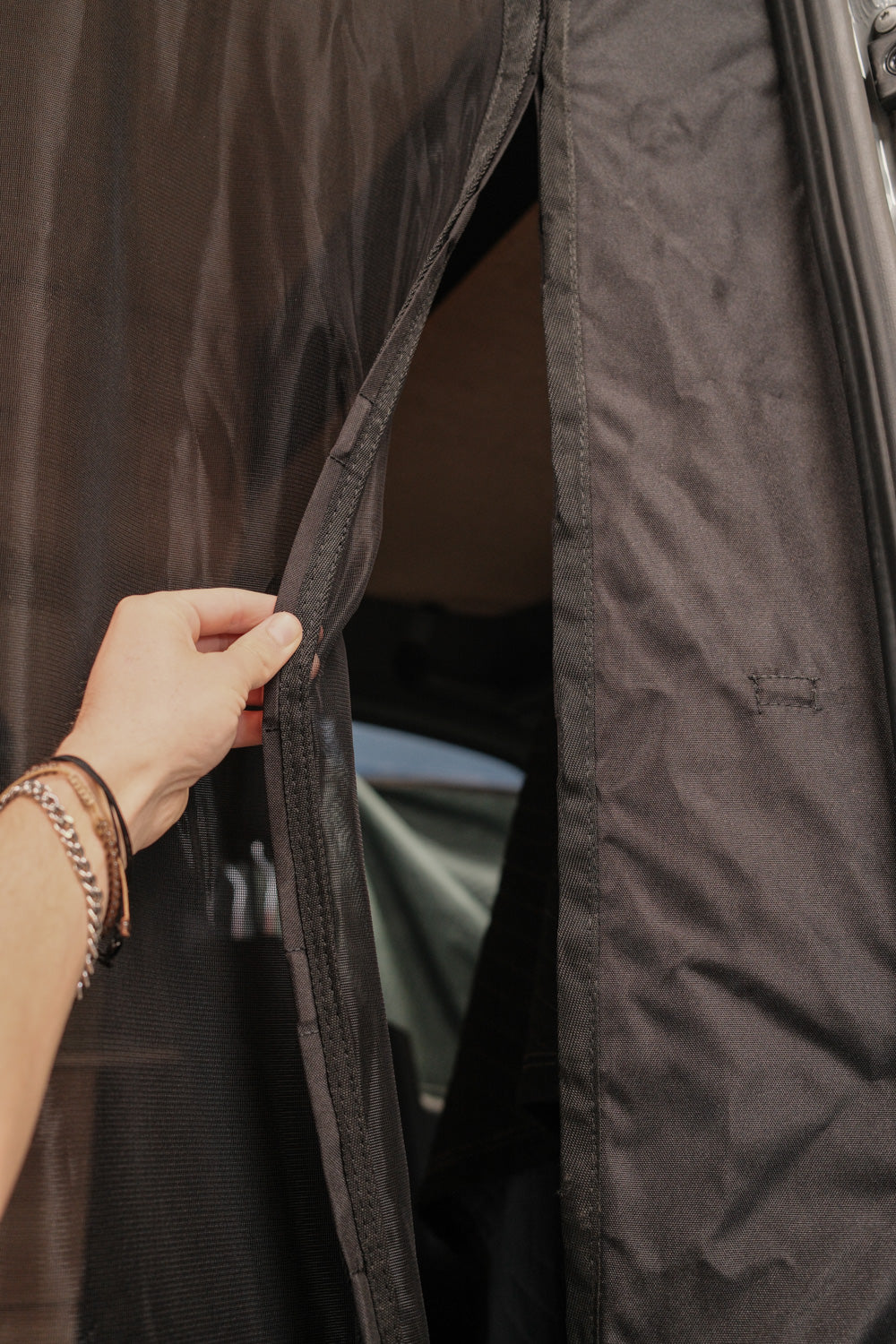 Hand pulling open the side magnet closure on a Sprinter van bug screen