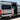 Custom white Sprinter van with open side door, roof rack, and off-road tires, parked outdoors.