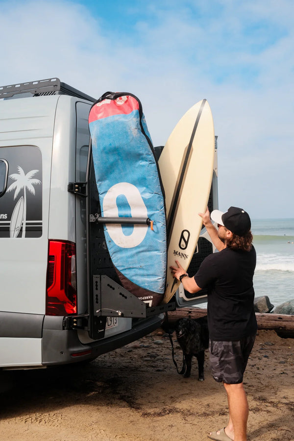Man loading surfboards into custom van at beach, ready for coastal adventure