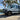 Custom Sprinter adventure van with off-road tires parked by a scenic lakeside forest